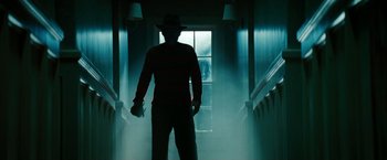 Movie still from “A Nightmare on Elm Street” (2010), directed by Samuel Bayer – A man standing in a dark hallway holding a glove; Medium shot, Low angle