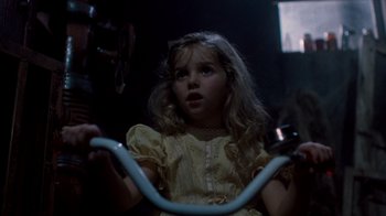 Movie still from “A Nightmare on Elm Street 3: Dream Warriors” (1987), directed by Chuck Russell – A little girl in a yellow dress riding a bike; Close Up shot, Over the shoulder angle