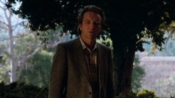 Movie still from “A Nightmare on Elm Street 3: Dream Warriors” (1987), directed by Chuck Russell – A man wearing a suit and tie standing next to a tree; Medium shot, Low angle