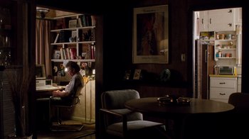 Movie still from “A Nightmare on Elm Street 3: Dream Warriors” (1987), directed by Chuck Russell – A person sitting at a desk in a room with bookshelves; Wide shot, High angle