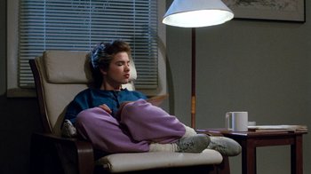 Movie still from “A Nightmare on Elm Street 3: Dream Warriors” (1987), directed by Chuck Russell – A person sitting in a chair in a living room; Medium shot, High angle