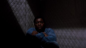 Movie still from “A Nightmare on Elm Street 3: Dream Warriors” (1987), directed by Chuck Russell – A man sitting in the dark with his arms crossed; Medium shot, High angle