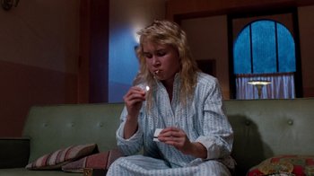 Movie still from “A Nightmare on Elm Street 3: Dream Warriors” (1987), directed by Chuck Russell – A woman sitting on a couch smoking a cigarette; Medium shot, Low angle