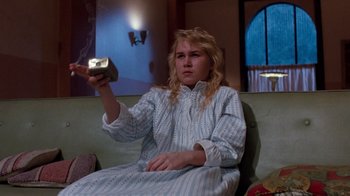 Movie still from “A Nightmare on Elm Street 3: Dream Warriors” (1987), directed by Chuck Russell – A woman sitting on a couch holding a remote control; Medium shot, Low angle
