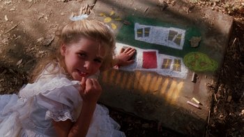 Movie still from “A Nightmare on Elm Street 4: The Dream Master” (1988), directed by Renny Harlin – A little girl in a white dress is sitting in front of a house drawn on the ground; Close Up shot, High angle