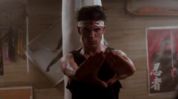 Movie still from “A Nightmare on Elm Street 4: The Dream Master” (1988), directed by Renny Harlin – A man in a headband making a heart with his hands; Medium shot, Low angle