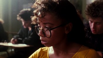 Movie still from “A Nightmare on Elm Street 4: The Dream Master” (1988), directed by Renny Harlin – A woman with glasses looking to her left; Close Up shot, Over the shoulder angle