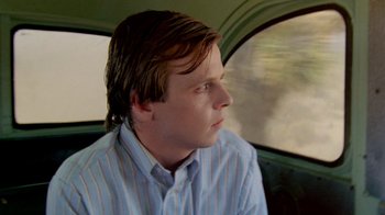 Movie still from “A Nightmare on Elm Street 2: Freddy's Revenge” (1985), directed by Jack Sholder – A man sitting in the back seat of a car looking out the window; Close Up shot, Over the shoulder angle