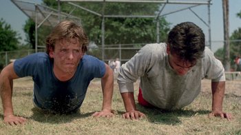 Movie still from “A Nightmare on Elm Street 2: Freddy's Revenge” (1985), directed by Jack Sholder – Two young men are laying in the grass; Medium shot, Low angle