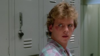 Movie still from “A Nightmare on Elm Street 2: Freddy's Revenge” (1985), directed by Jack Sholder – A young man in plaid shirt in front of lockers; Close Up shot, Over the shoulder angle