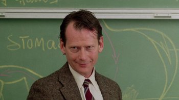 Movie still from “A Nightmare on Elm Street 2: Freddy's Revenge” (1985), directed by Jack Sholder – A man wearing a suit and tie standing in front of a chalkboard; Close Up shot, Low angle