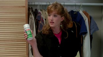 Movie still from “A Nightmare on Elm Street 2: Freddy's Revenge” (1985), directed by Jack Sholder – A woman holding up a can of deodorant in front of a closet; Close Up shot, Over the shoulder angle