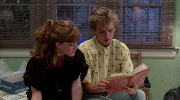 Movie still from “A Nightmare on Elm Street 2: Freddy's Revenge” (1985), directed by Jack Sholder – A man and a woman are looking at a book; Medium shot, Low angle