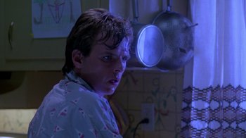 Movie still from “A Nightmare on Elm Street 2: Freddy's Revenge” (1985), directed by Jack Sholder – A young man in a nightshirt in front of a mirror; Medium shot, Low angle