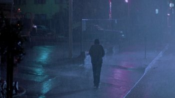 Movie still from “A Nightmare on Elm Street 2: Freddy's Revenge” (1985), directed by Jack Sholder – A person walking down a street in the rain; Extreme Wide shot, High angle