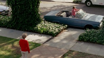 Movie still from “A Nightmare on Elm Street 2: Freddy's Revenge” (1985), directed by Jack Sholder – A woman in a red shirt is standing next to a blue car; Extreme Wide shot, High angle