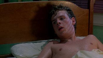 Movie still from “A Nightmare on Elm Street 2: Freddy's Revenge” (1985), directed by Jack Sholder – A man laying in a bed covered in water; Medium shot, High angle