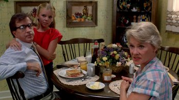 Movie still from “A Nightmare on Elm Street 2: Freddy's Revenge” (1985), directed by Jack Sholder – Two women and a girl sitting at a table with food; Medium shot, Over the shoulder angle
