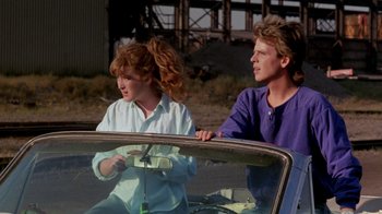 Movie still from “A Nightmare on Elm Street 2: Freddy's Revenge” (1985), directed by Jack Sholder – A man and a woman sitting in the back seat of a car; Medium shot, Low angle