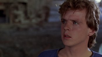 Movie still from “A Nightmare on Elm Street 2: Freddy's Revenge” (1985), directed by Jack Sholder – A young man looking at the camera in a dark room; Close Up shot, Over the shoulder angle