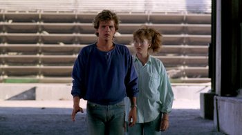 Movie still from “A Nightmare on Elm Street 2: Freddy's Revenge” (1985), directed by Jack Sholder – A man and a woman standing next to each other in front of bleachers; Medium shot, Low angle