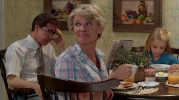 Movie still from “A Nightmare on Elm Street 2: Freddy's Revenge” (1985), directed by Jack Sholder – A woman sitting at a table holding a sandwich and drinking a beverage; Medium shot, Over the shoulder angle