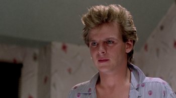 Movie still from “A Nightmare on Elm Street 2: Freddy's Revenge” (1985), directed by Jack Sholder – A young man with spiky blonde hair stares into the camera; Close Up shot, Low angle