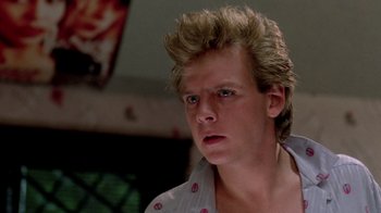 Movie still from “A Nightmare on Elm Street 2: Freddy's Revenge” (1985), directed by Jack Sholder – A young man with spiky blond hair stares into the camera; Close Up shot, Low angle