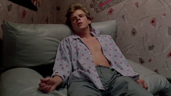 Movie still from “A Nightmare on Elm Street 2: Freddy's Revenge” (1985), directed by Jack Sholder – A man laying on a couch with his shirt open; Medium shot, High angle