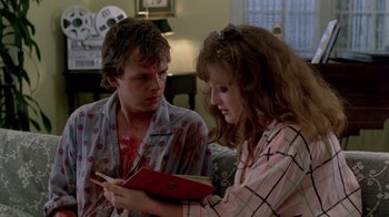 Movie still from “A Nightmare on Elm Street 2: Freddy's Revenge” (1985), directed by Jack Sholder – A man and a woman are looking at a book; Medium shot, Over the shoulder angle