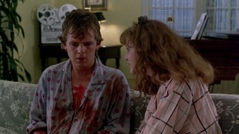 Movie still from “A Nightmare on Elm Street 2: Freddy's Revenge” (1985), directed by Jack Sholder – A man and a woman sitting in a living room; Medium shot, Over the shoulder angle