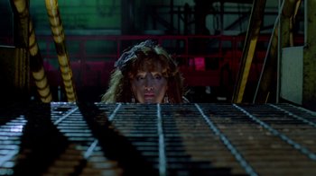 Movie still from “A Nightmare on Elm Street 2: Freddy's Revenge” (1985), directed by Jack Sholder – A woman looking over a metal grate in an industrial setting; Close Up shot, Low angle