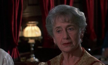Movie still from “A Passage to India” (1984), directed by David Lean – An older woman with grey hair sitting in front of a lamp; Close Up shot, Over the shoulder angle