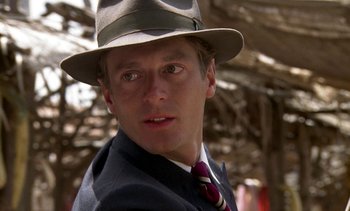 Movie still from “A Passage to India” (1984), directed by David Lean – A person wearing a suit and hat; Close Up shot, Over the shoulder angle