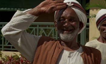 Movie still from “A Passage to India” (1984), directed by David Lean – An older man in a turban saluting with one hand; Close Up shot, Low angle