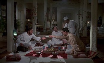 Movie still from “A Passage to India” (1984), directed by David Lean – A group of men sitting around a table; Wide shot, High angle