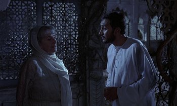 Movie still from “A Passage to India” (1984), directed by David Lean – A man and a woman are talking in front of a wall; Medium shot, Over the shoulder angle
