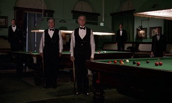 Movie still from “A Passage to India” (1984), directed by David Lean – Two men standing in front of a pool table; Wide shot, Low angle