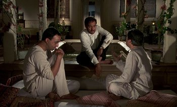 Movie still from “A Passage to India” (1984), directed by David Lean – A group of men sitting on the ground in a room; Wide shot, High angle