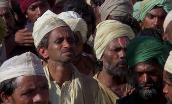 Movie still from “A Passage to India” (1984), directed by David Lean – A group of men wearing turbans in a crowd of people; Medium shot, High angle