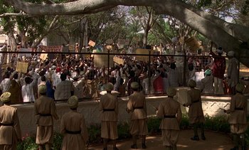 Movie still from “A Passage to India” (1984), directed by David Lean – A group of people standing in front of a crowd; Extreme Wide shot, High angle