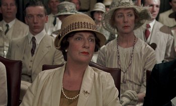 Movie still from “A Passage to India” (1984), directed by David Lean – An older woman wearing a hat sitting in front of a group of people; Close Up shot, High angle