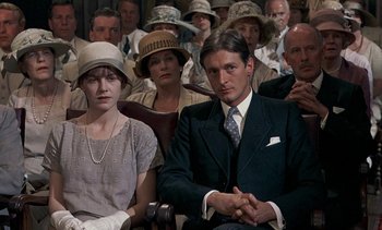 Movie still from “A Passage to India” (1984), directed by David Lean – A man and woman sitting in a crowd of people; Medium shot, High angle