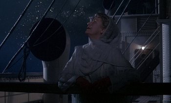 Movie still from “A Passage to India” (1984), directed by David Lean – A woman in a white coat looking up at the sky; Medium shot, Low angle