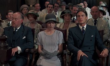 Movie still from “A Passage to India” (1984), directed by David Lean – A group of people sitting in a room with hats on; Medium shot, High angle