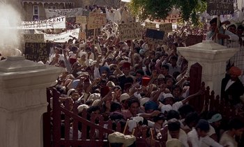 Movie still from “A Passage to India” (1984), directed by David Lean – A large crowd of people holding up signs and protesting; Extreme Wide shot, High angle