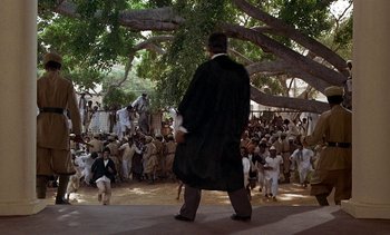 Movie still from “A Passage to India” (1984), directed by David Lean – A crowd of people gathered under a large tree; Extreme Wide shot, High angle