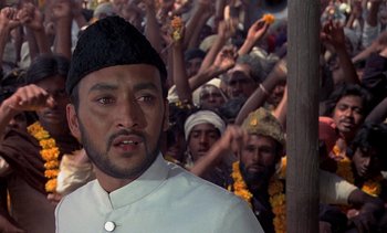 Movie still from “A Passage to India” (1984), directed by David Lean – A group of men in a crowd of people; Close Up shot, Low angle