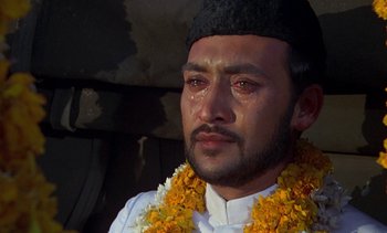 Movie still from “A Passage to India” (1984), directed by David Lean – A person with a flower garland around his neck; Close Up shot, Low angle