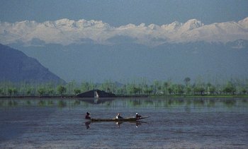 Movie still from “A Passage to India” (1984), directed by David Lean – Two people are rowing a canoe across a body of water; Extreme Wide shot, High angle